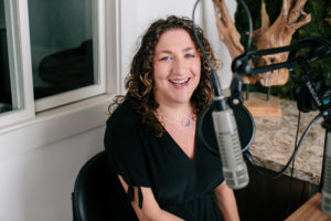 Woman smiling sitting next to a microphone