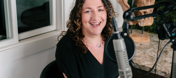 Woman smiling sitting next to a microphone
