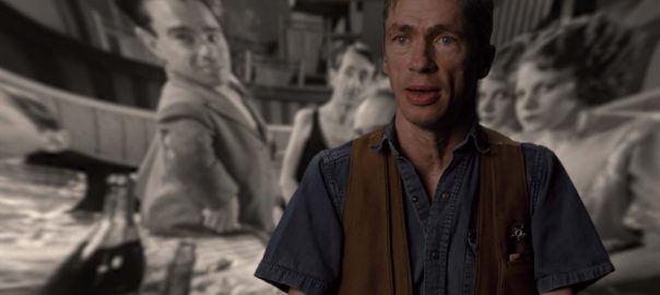 a man sits in front of a projected black and white image