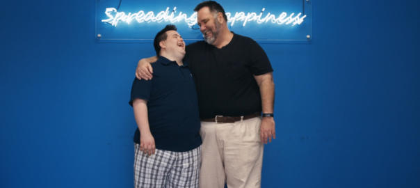 A father and son stand under a neon sign