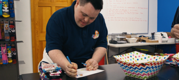 a man leans over a table writing a note