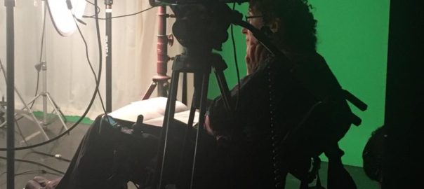 image of Susan Nussbaum sitting in a chair next to a camera