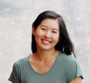 a young asian woman with long brown hair, wearing a green, round collared t-shirt