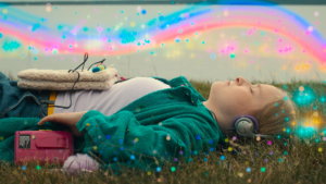 A young person lies on their back in a grassy field, eyes closed, wearing headphones and with a pink cassette player nearby. Colorful light effects and sparkles overlay the image