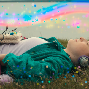 A young person lies on their back in a grassy field, eyes closed, wearing headphones and with a pink cassette player nearby. Colorful light effects and sparkles overlay the image