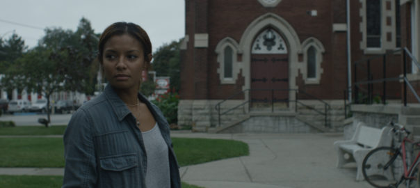 a woman stands in front of a church in the background
