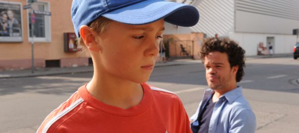 A man looks at a boy in a baseball cap