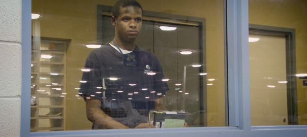 A man looks through a glass window. Littles are reflected in the window