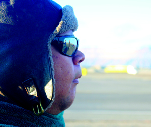 A man with glasses and a winter hat looks out