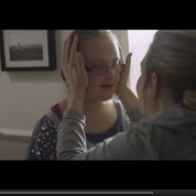 A woman has her hands on the face of another person in front of her