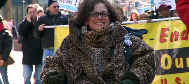a woman in a wheelchair participates in a protest march