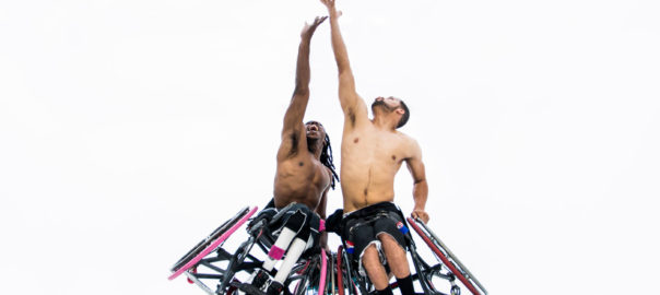 Two people in wheelchairs compete in a basketball tip off