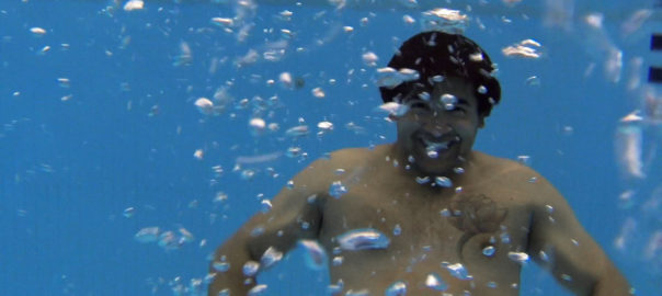 A man is submerged in water with bubbles around him