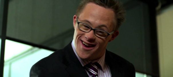 A man in a suit smiles looking down