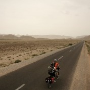 A person travels down a long empty road in a desert