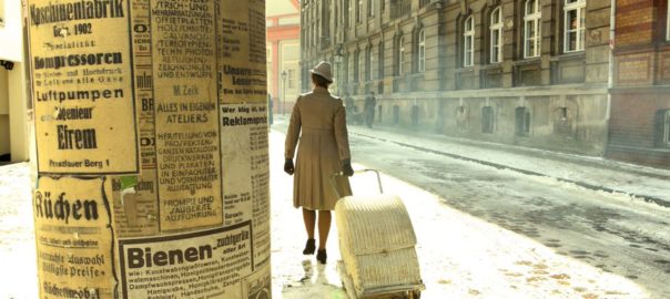 A man wheels a suitcase away from a pole covered in posters