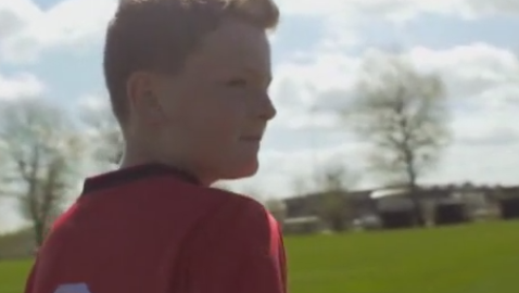 A boy in a red shirt stands in a field