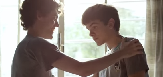 A teenager has his hands on another teenager's shoulders