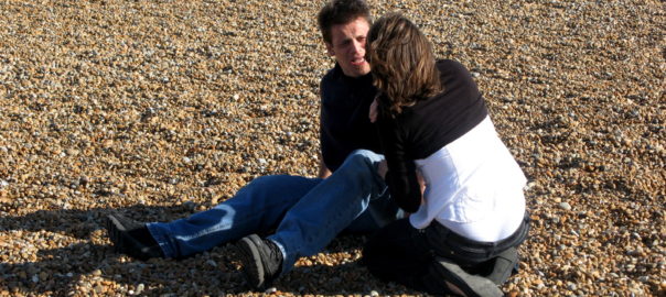 A woman sits next to a man on the ground