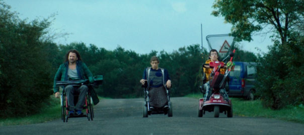 Three people in wheelchairs on a road