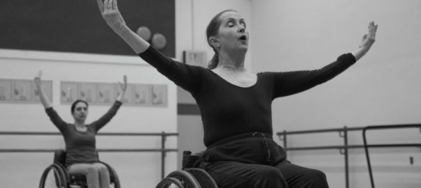 Two women have their arms raised in a dance studio