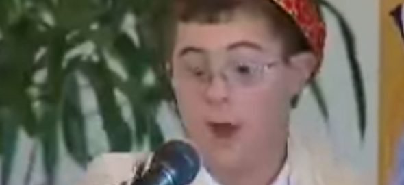 A boy in a kippah speaks into a microphone