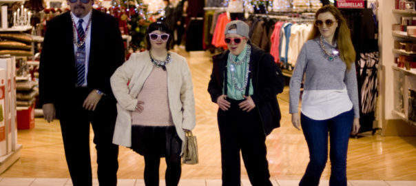 A group of people pose in front of a clothing store