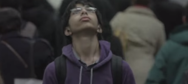 A boy with a backpack looks up