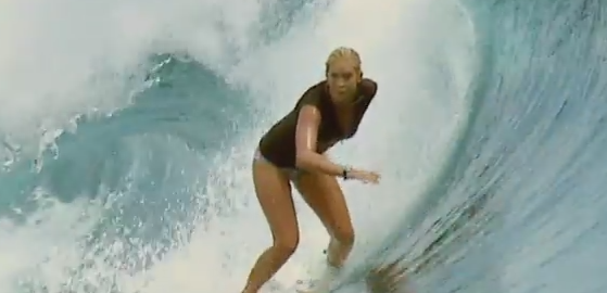 A woman with one arm surfs a large wave