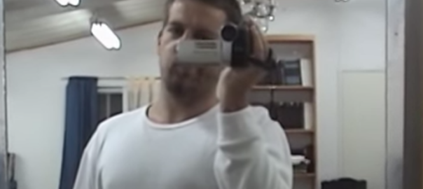 A man films himself with a videocamera in front of a mirror