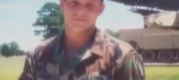 A man in a military uniform poses in front of a helicopter