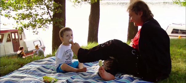 a person sits on a picnic blanket with a child