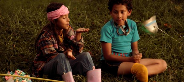Two children sit on grass