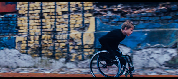 A person in a wheelchair moves down a street