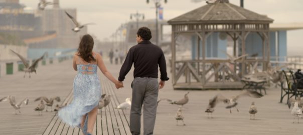 A man and women walk down a boardwalk holding hands