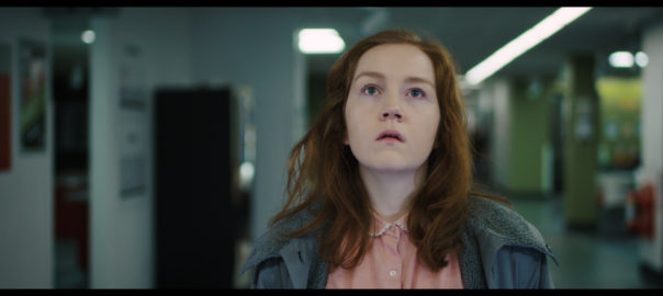 A girl stands in a hallway looking up