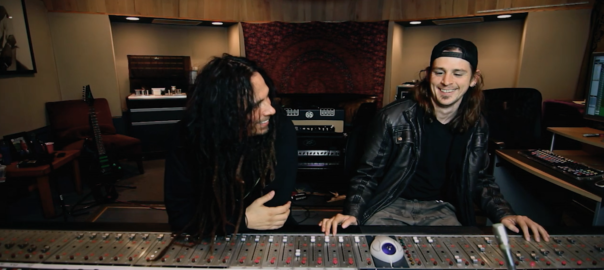 Two people sit in front of a sound mixing board
