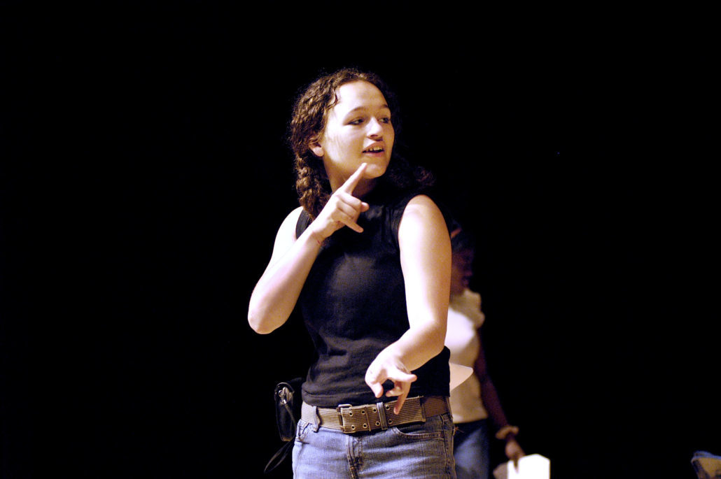 A woman in a black shirt and jeans signs