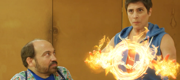 A woman has a ring of fire in front of her. A man stands next to her.