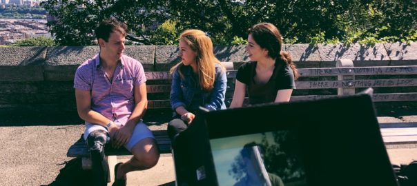 Three people sit on a bench