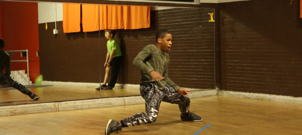 A boy dances in front of a mirror