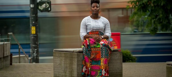 A woman sits on a bench in a colorful skirt