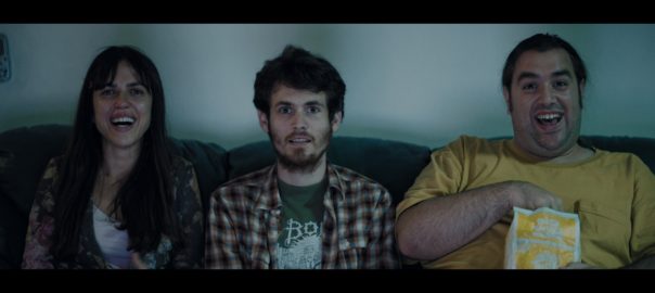 A woman and two men sit on a couch