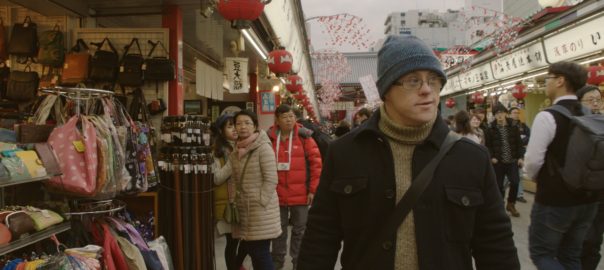 A man in a jacket and hat walks through a market