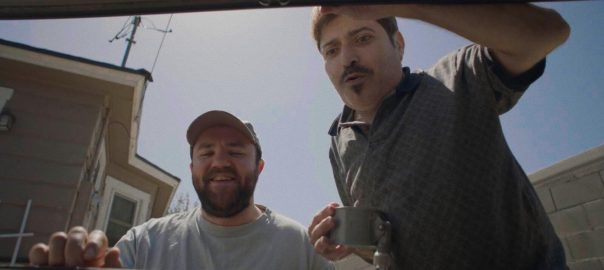 Two men look into a car trunk