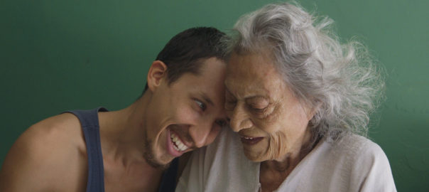 A man leans his head onto his grandmother's shoulder