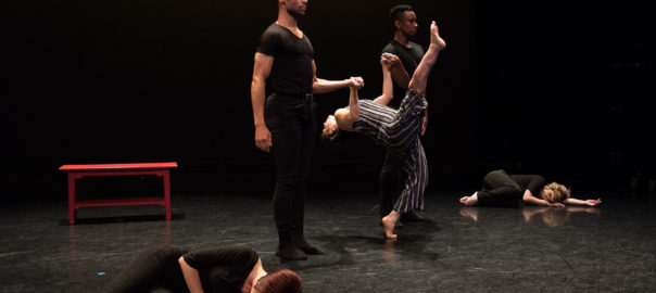 a woman kicks her leg in the air while supported by two men