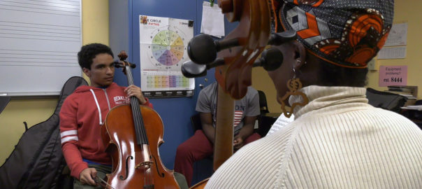 Adam plays a cello in class with an instructor
