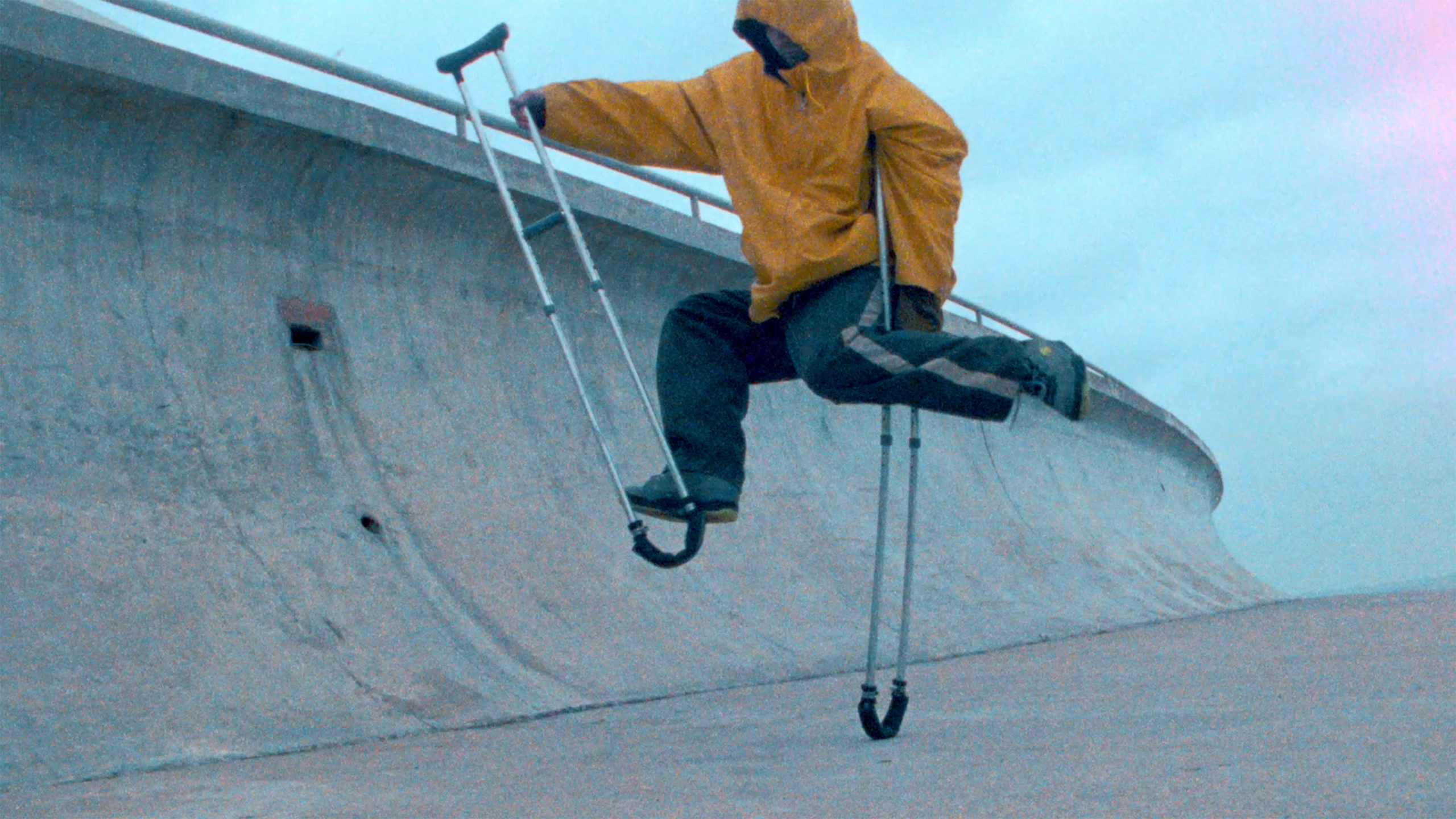 Bill Shannon in a yellow rain jacket dances on crutches