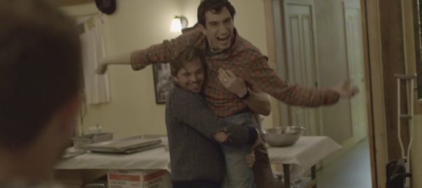 A person picks up a man who is celebrating with his arms in the air.